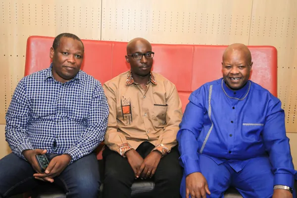 Trois invités assis sur une banquette rouge